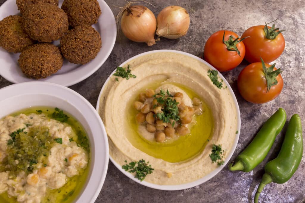 Houmous et falafels frais pour un repas méditerranéen Assiette de houmous onctueux, falafels dorés, tomates et piments frais pour un repas méditerranéen savoureux.